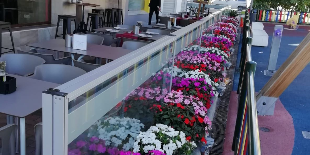 paravientos en hostelería con maceteros llenos de flores