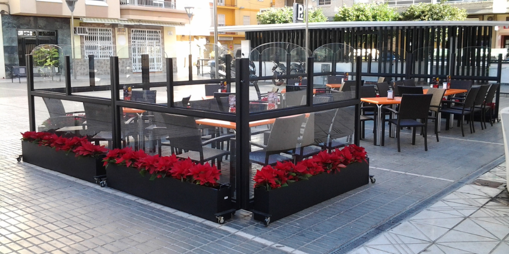 paravientos de cristal con maceteros para mejorar el ambiente de la terraza de un bar