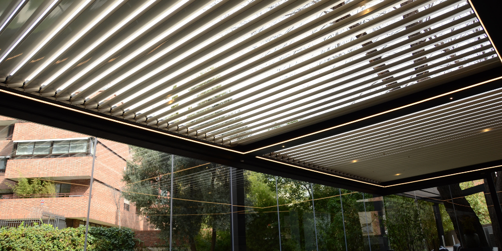 Ejemplos de pérgolas bioclimáticas en hostelería con cortinas de cristal abatibles sin guía inferior